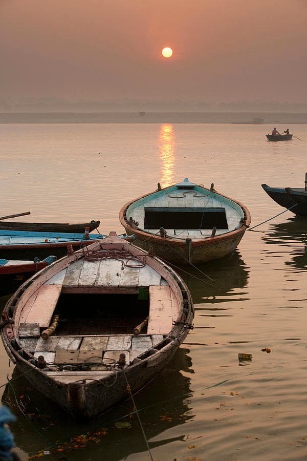 Wooden boats on the Ganga as a red sun rises over Varanasi