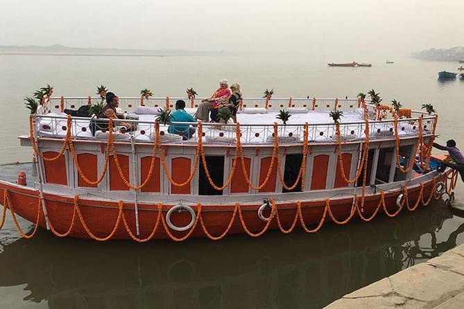 Marigold-decorated GhatGo experience boat moored at a Varanasi ghat